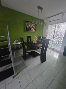 ein Esszimmer mit grünen Wänden und einem Tisch und Stühlen in der Unterkunft Casa NK in Tierra Colorada