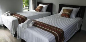 two beds in a bedroom with white sheets and a window at sengjan garden krabi in Ban Khlong Son