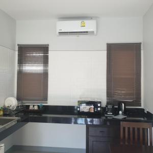 a kitchen with a black counter top and two windows at sengjan garden krabi in Ban Khlong Son