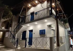 a white building with blue doors and stairs at night at Kea's Living Yard II in Korissia