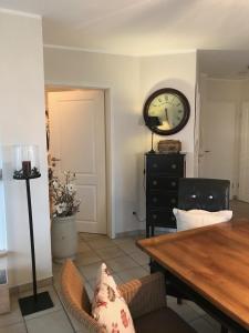 a dining room with a table and a clock on the wall at Godeke Michels Ferienwohnung 21 Seestr5b in Groß Kirr