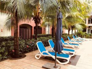 a row of lounge chairs and an umbrella at Enjoy at Your Own Luxurious Home with LPG Pool Net in Arpora