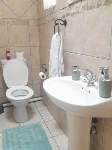 Un baño con un lavabo blanco y un inodoro. en TANS Guest suite, en Centurion