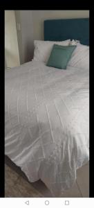 a white bed with a green pillow on it at Lerato's Guesthouse in Polokwane