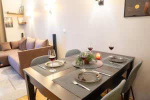 a dining room table with wine glasses and a couch at Hygge Oasis for family with free parking and wi fi in Vilnius