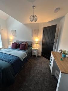 a bedroom with a large bed with purple pillows at Cannons Loft Central Buxton, Duplex loft 3 bedroom Set over 3 floors stairs no lift sleeps 5 in Buxton