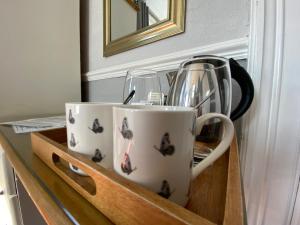 two coffee cups and glasses sitting in a wooden drawer at Goodwin House in Keswick