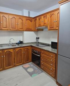Una cocina con gabinetes de madera, un fregadero y un refrigerador. en Balcón de Puerto Naos, en Los Llanos de Aridane