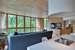 a living room with a blue couch and some windows at Chesa Gravules - La Punt in La Punt-Chamues-ch