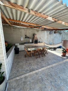 a patio with a table and chairs under a roof at Rancho Lopes - Casa com piscina e churrasqueira, Iguape-SP in Iguape