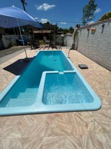 a large blue swimming pool on a patio with an umbrella at Rancho Lopes - Casa com piscina e churrasqueira, Iguape-SP in Iguape