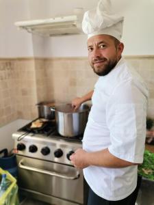 a chef standing in a kitchen holding a pot at Pensiunea Bibanu in Mineri