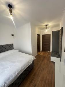 a bedroom with a white bed and a wooden floor at Pensiunea Bibanu in Mineri +25 photos