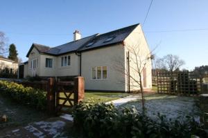 een wit huis met een hek ervoor bij Heatherlea Holiday Cottage in Otterburn