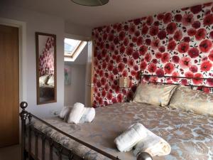 een slaapkamer met een groot bed met rode bloemen aan de muur bij Heatherlea Holiday Cottage in Otterburn