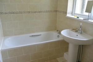 een badkamer met een wit bad en een wastafel bij Heatherlea Holiday Cottage in Otterburn +17 foto's