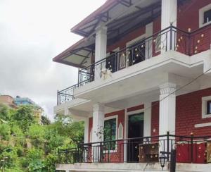 a large red and white building with a balcony at Bindabashini homestay house no 14 in Bandipur