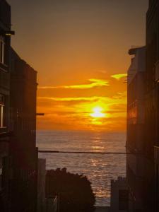 una puesta de sol sobre el océano entre dos edificios en Balcón de Puerto Naos, en Los Llanos de Aridane