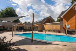 a house with a swimming pool in front of a house at Charmant chalet te Voorthuizen in Voorthuizen