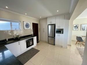 a kitchen with white cabinets and a stainless steel refrigerator at Ideal location, Mouille Point in Cape Town