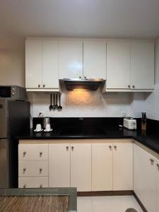 eine Küche mit weißen Schränken und einer schwarzen Arbeitsplatte in der Unterkunft Sheryll Escapes - La Grande 406 cozy 1 bedroom Wi-Fi and Netflix in Angeles