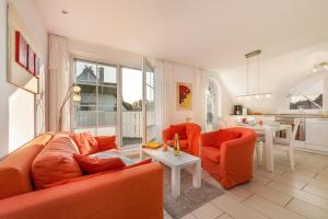 a living room with orange furniture and a kitchen at Godeke Michels Ferienwohnung 23-Jonggöntje Seestr5b in Groß Kirr +14 photos