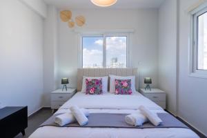 a white bedroom with a large white bed with pillows at Snobby 2-Bedroom Apartment in Larnaca