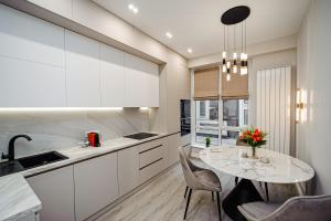 a white kitchen with a table and chairs at Eminescu Residence! in Chişinău