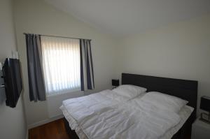 a bedroom with a bed with white sheets and a window at Gartenhaus 2, inkl 1 Parkplatz in Fehmarn