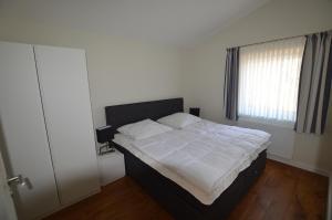 a bedroom with a bed with white sheets and a window at Gartenhaus 2, inkl 1 Parkplatz in Fehmarn