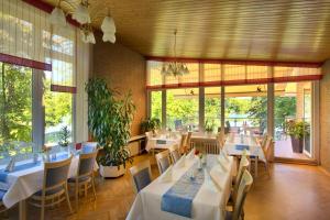 a restaurant with white tables and chairs and windows at Seehotel Ichlim in Lärz