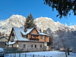 Una casa en la nieve con montañas al fondo en Casa Olivia, en Buşteni
