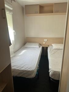 two beds in a small room with white sheets at Mobil-home tout équipé à louer in Villeneuve-lès-Maguelonne