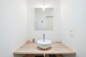 a bathroom with a white bowl sink on a wooden counter at Grand Central Suites - 4 Chambres Premium in Pau