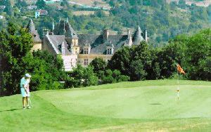 a man standing on a golf course with a castle at Les appart'hotels de la fontaine in Autoire