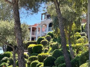 une grande maison blanche entourée d'arbres et de buissons dans l'établissement Cap esterel magnifique T3, à Saint-Raphaël