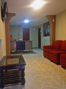 a living room with a red couch and a tv at Hostal Sauna Tambo Wasi in Huancayo