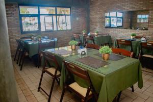 a restaurant with green tables and chairs and windows at Hotel Pousada Do Lago in Campo Maior