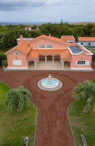 una grande casa rosa con una fontana nel cortile di Paradise Guest House a Farroupo