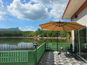 a patio with an umbrella and a view of a lake at Aonang Riverside Home in Ban Khlong Son