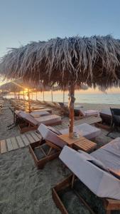 a beach with a straw umbrella and tables and chairs at Villa Sonja in Neoi Epivates