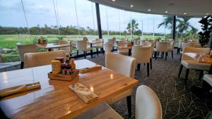a dining room with tables and chairs and windows at Family-Friendly Divi Golf Resort Steps to the Beach and Pool in Palm-Eagle Beach