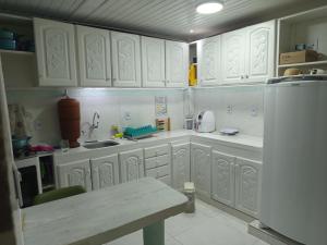 a kitchen with white cabinets and a refrigerator at Entre a paz e o canto dos pássaros in Manaus