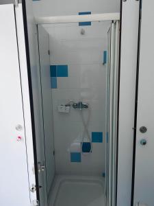 a glass shower with blue tiles in a bathroom at 70's Hostel in Ericeira