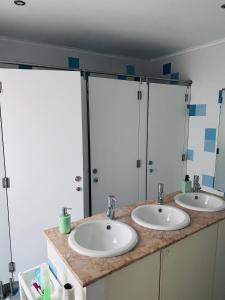 two sinks in a bathroom with two mirrors at 70's Hostel in Ericeira