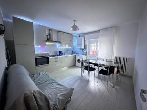 una cocina blanca con mesa y sillas. en INFONDOALMAR RIMINI --Intero Apt Indipendente-Netflix-MetroMare a 40m-Proiettore 4k Cinema-WiFi Fibra-Led-Parcheggio-Riscaldamento--, en Rímini