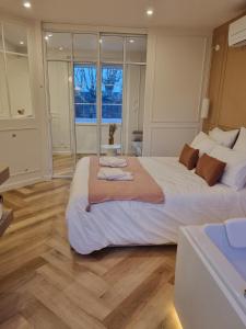 ein großes Schlafzimmer mit einem großen weißen Bett und Holzböden in der Unterkunft Le Boudoir d'Elba - Balneotherapie & terrasse in Meyssac