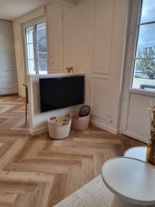 ein Wohnzimmer mit einem TV und Holzböden in der Unterkunft Le Boudoir d'Elba - Balneotherapie & terrasse in Meyssac