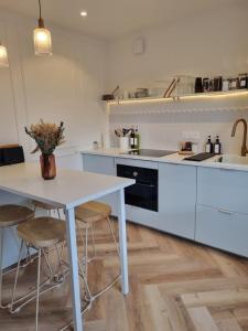 eine weiße Küche mit einem Tisch und Stühlen in der Unterkunft Le Boudoir d'Elba - Balneotherapie & terrasse in Meyssac