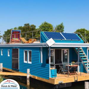 a blue tiny house with solar panels on the deck at Hausboot Isa - Huus & Meer in Großenbrode-Kai